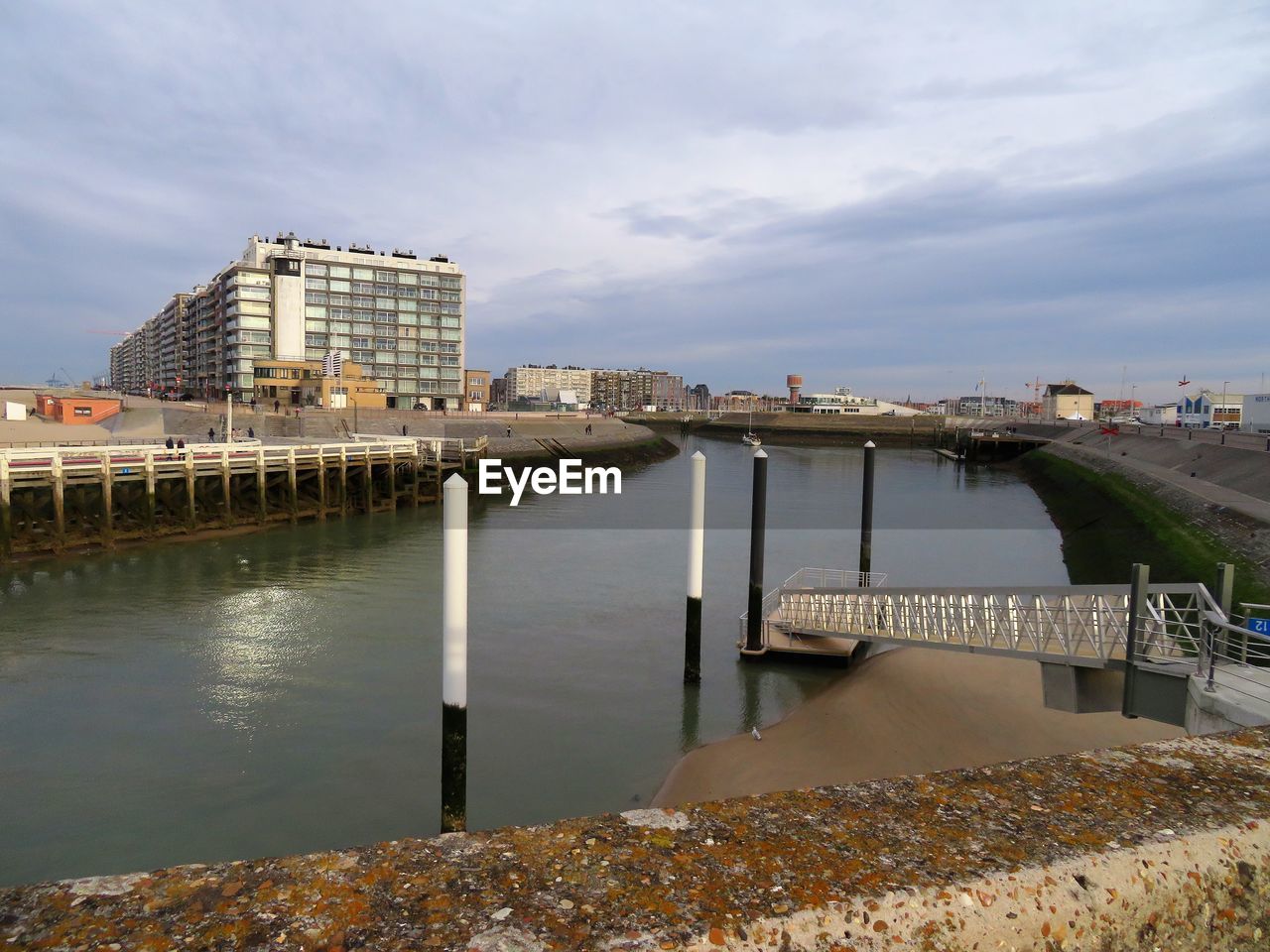 BRIDGE OVER RIVER BY BUILDINGS AGAINST SKY