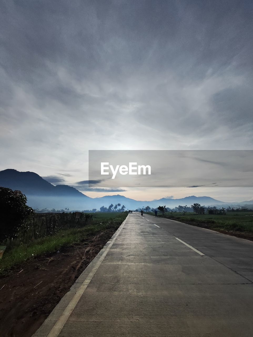 sky, horizon, road, cloud, transportation, environment, landscape, nature, mountain, the way forward, scenics - nature, travel, no people, beauty in nature, morning, highway, vanishing point, sunlight, land, dramatic sky, infrastructure, diminishing perspective, outdoors, non-urban scene, asphalt, light, travel destinations, sign, cloudscape, symbol, country road, tranquility, mode of transportation, road marking, mountain range, journey, dusk, street, marking, moody sky, day, plant, overcast