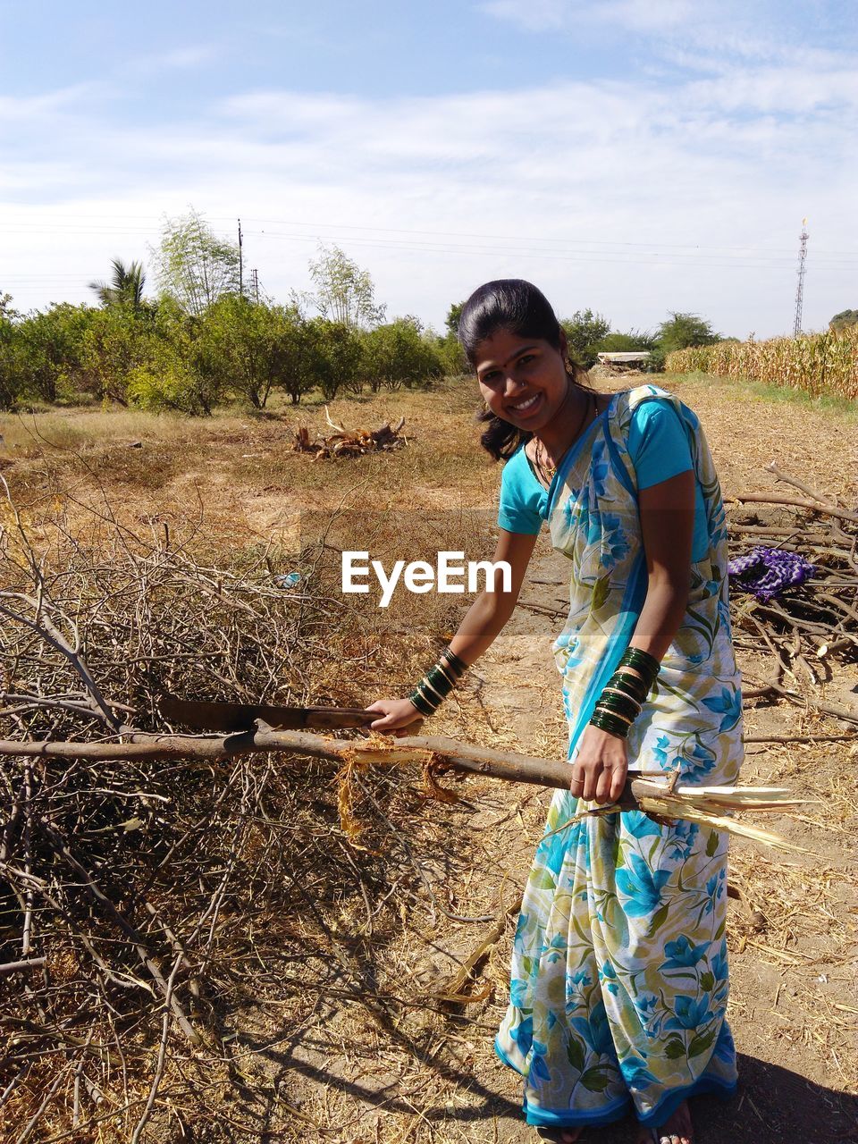 Portrait of woman cutting branches on land against sky