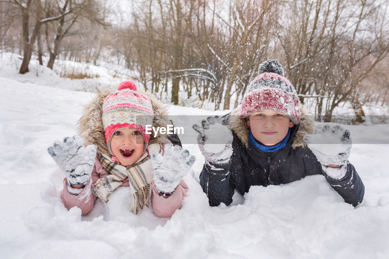 winter, cold temperature, snow, child, childhood, warm clothing, clothing, female, fun, nature, women, family, emotion, togetherness, happiness, hat, two people, smiling, portrait, glove, men, knit hat, enjoyment, leisure activity, positive emotion, toddler, tree, mitten, front view, sled, looking at camera, white, tobogganing, snowing, day, bonding, winter coat, outdoors, cheerful, friendship, laughing, cute, freezing, holiday, land, coat