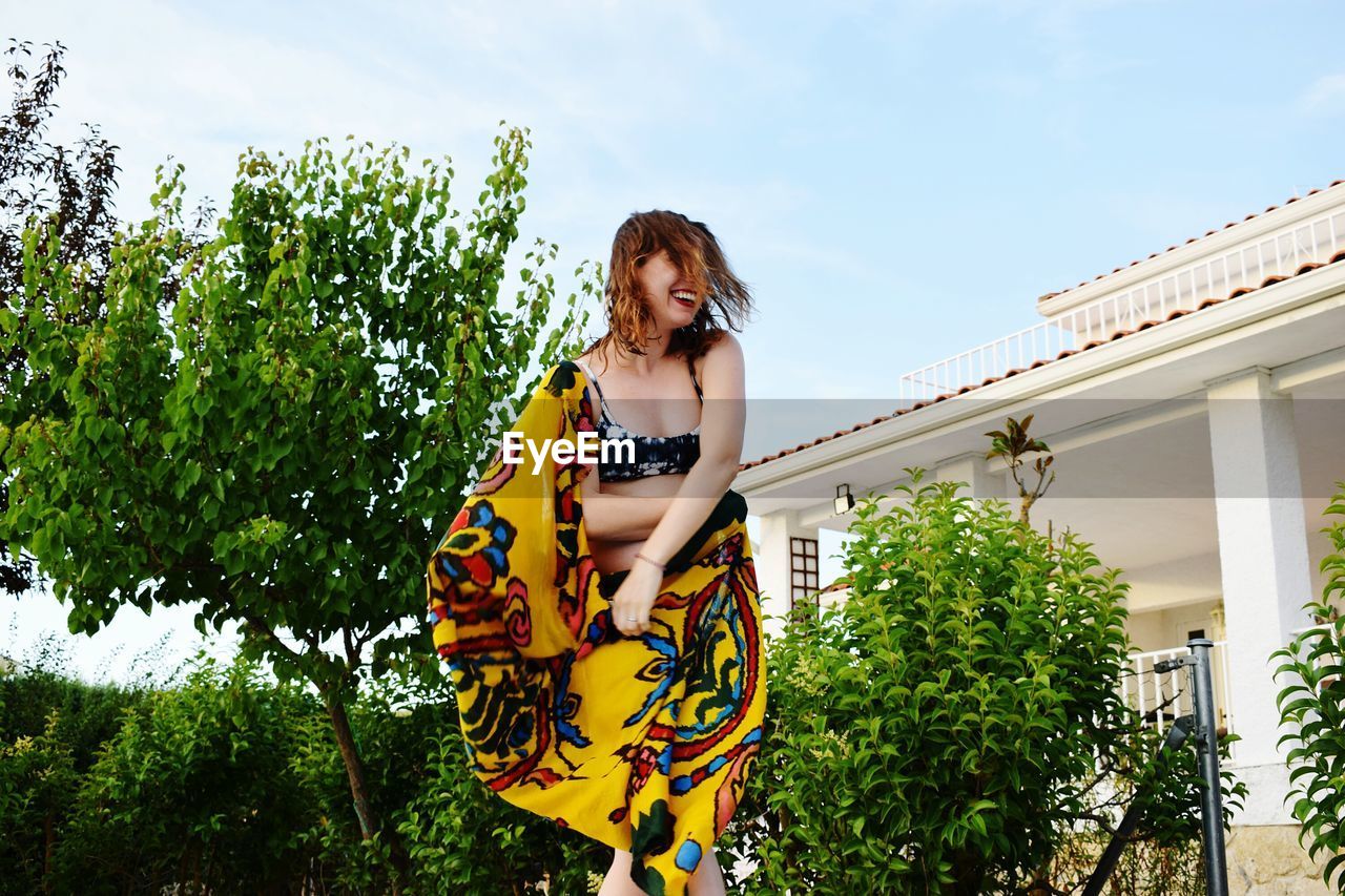 Low angle view of woman wearing sarong while standing against trees