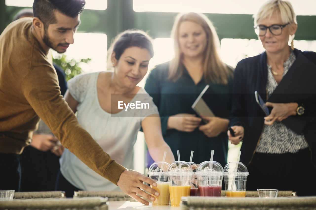 Business people picking up disposable cups of fresh juice in office