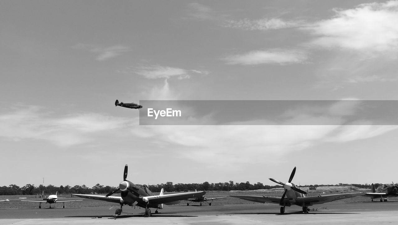 Airplane flying over airport runway against sky