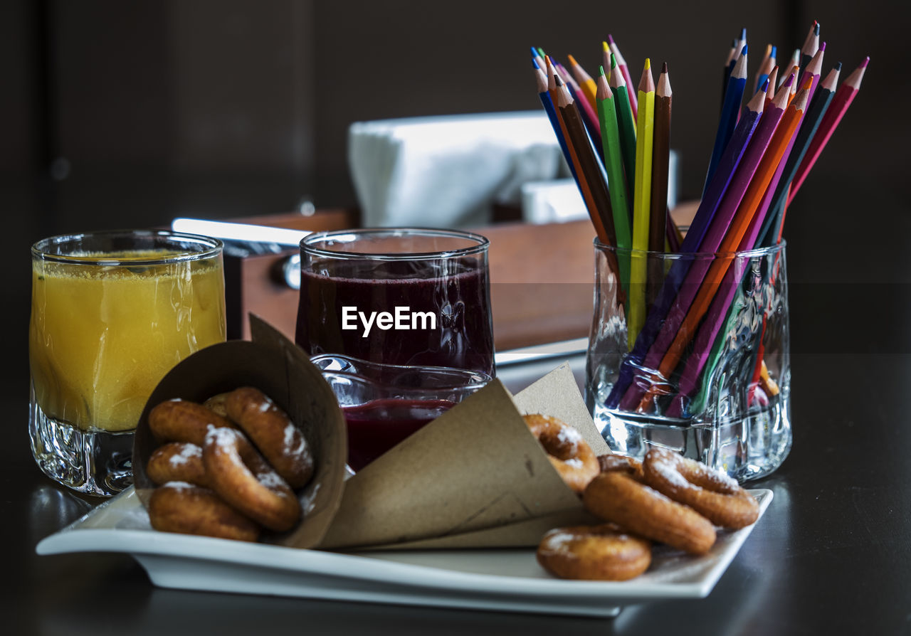 Close-up of food and drink in tray by colored pencils on table