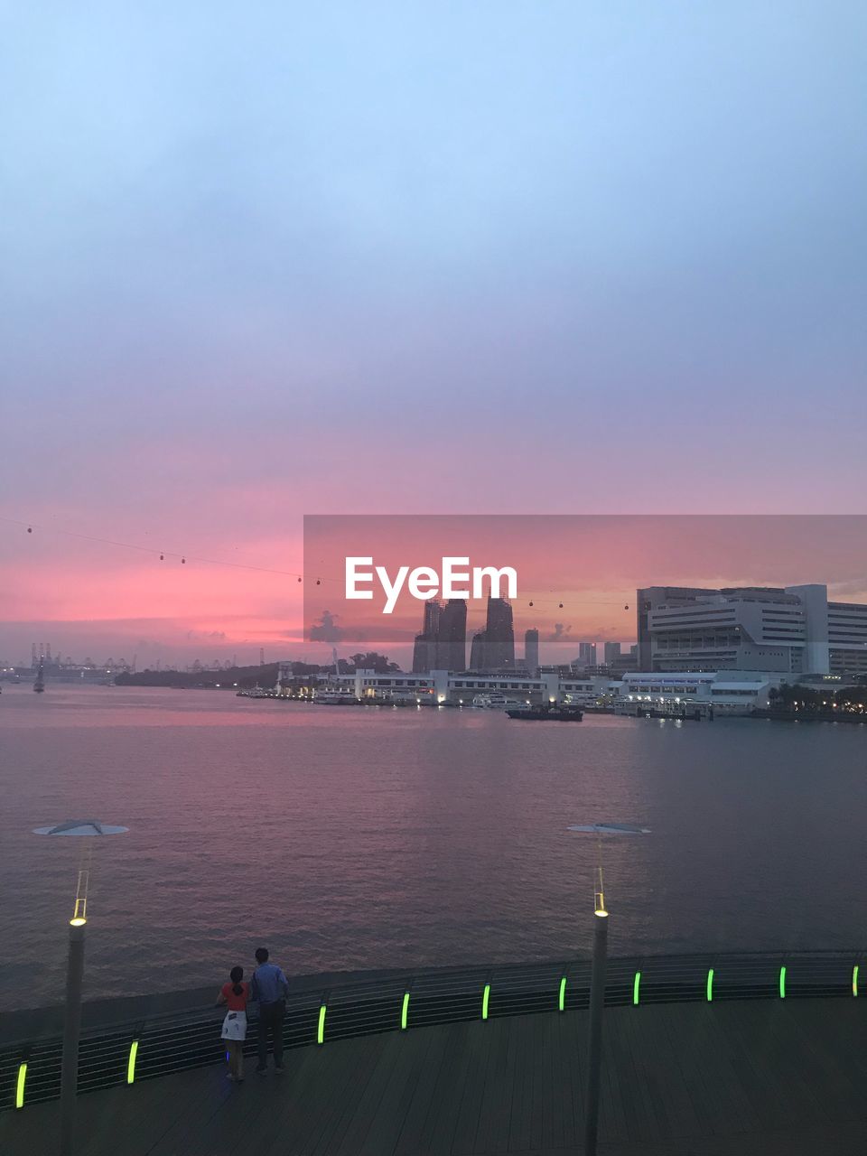 High angle view of sea by buildings against sky at sunset