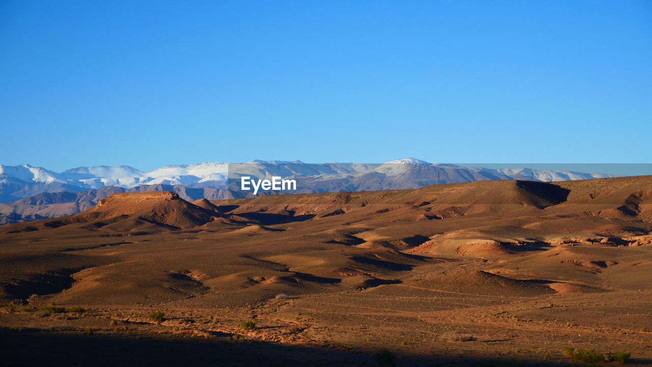 Scenic view of desert against clear blue sky