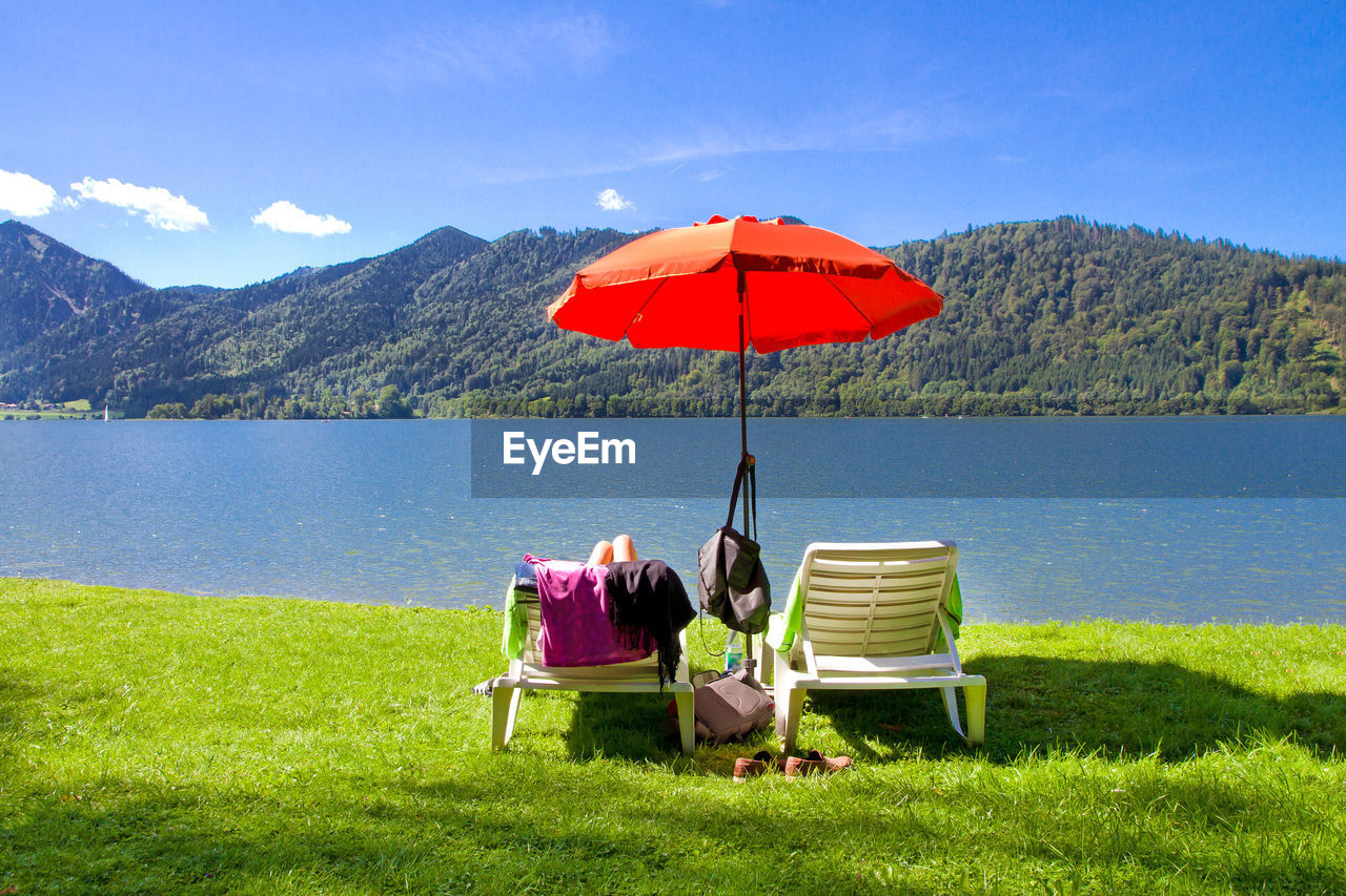 VIEW OF PEOPLE SITTING ON CHAIR BY LAKE