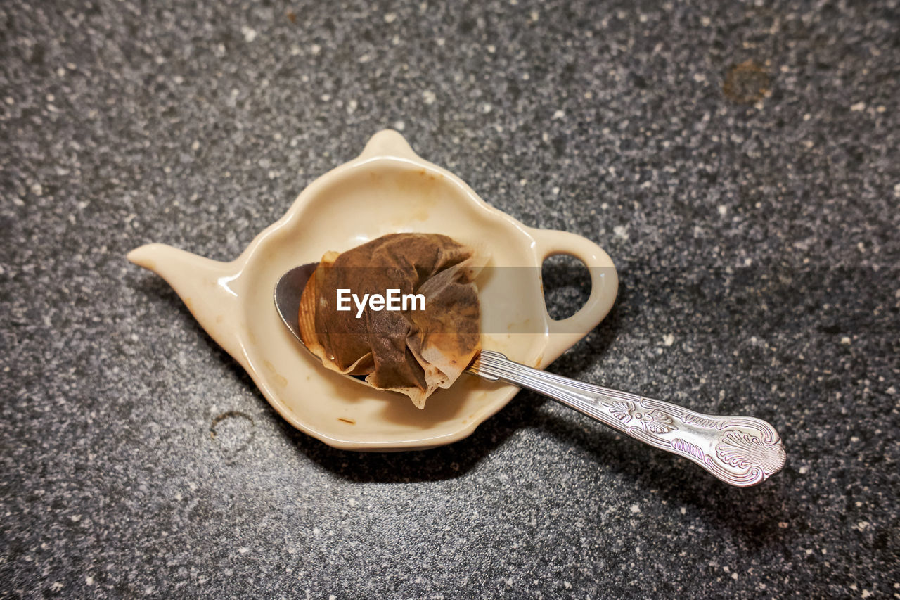 Close-up of teabag in teapot shaped plastic plate on table