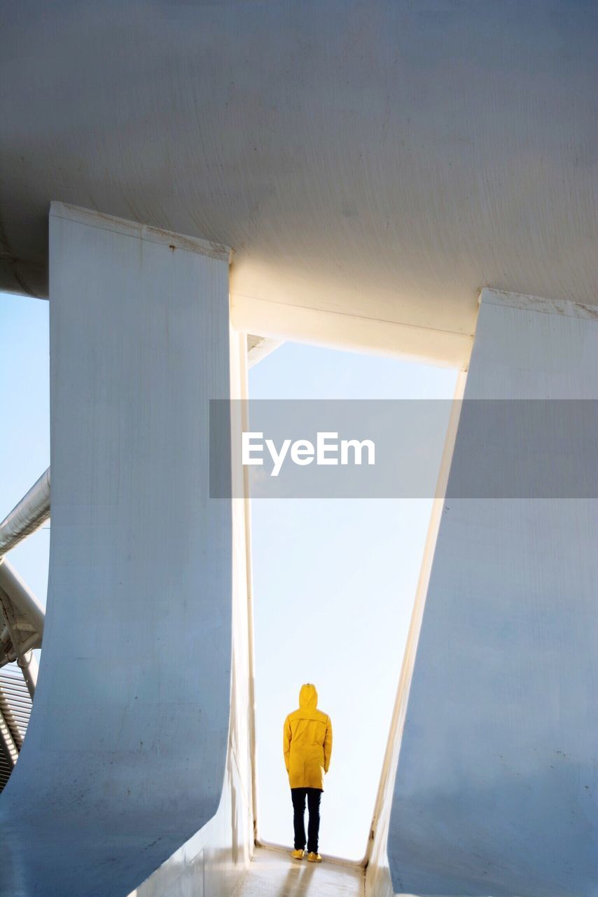 Rear view of person standing in building against sky