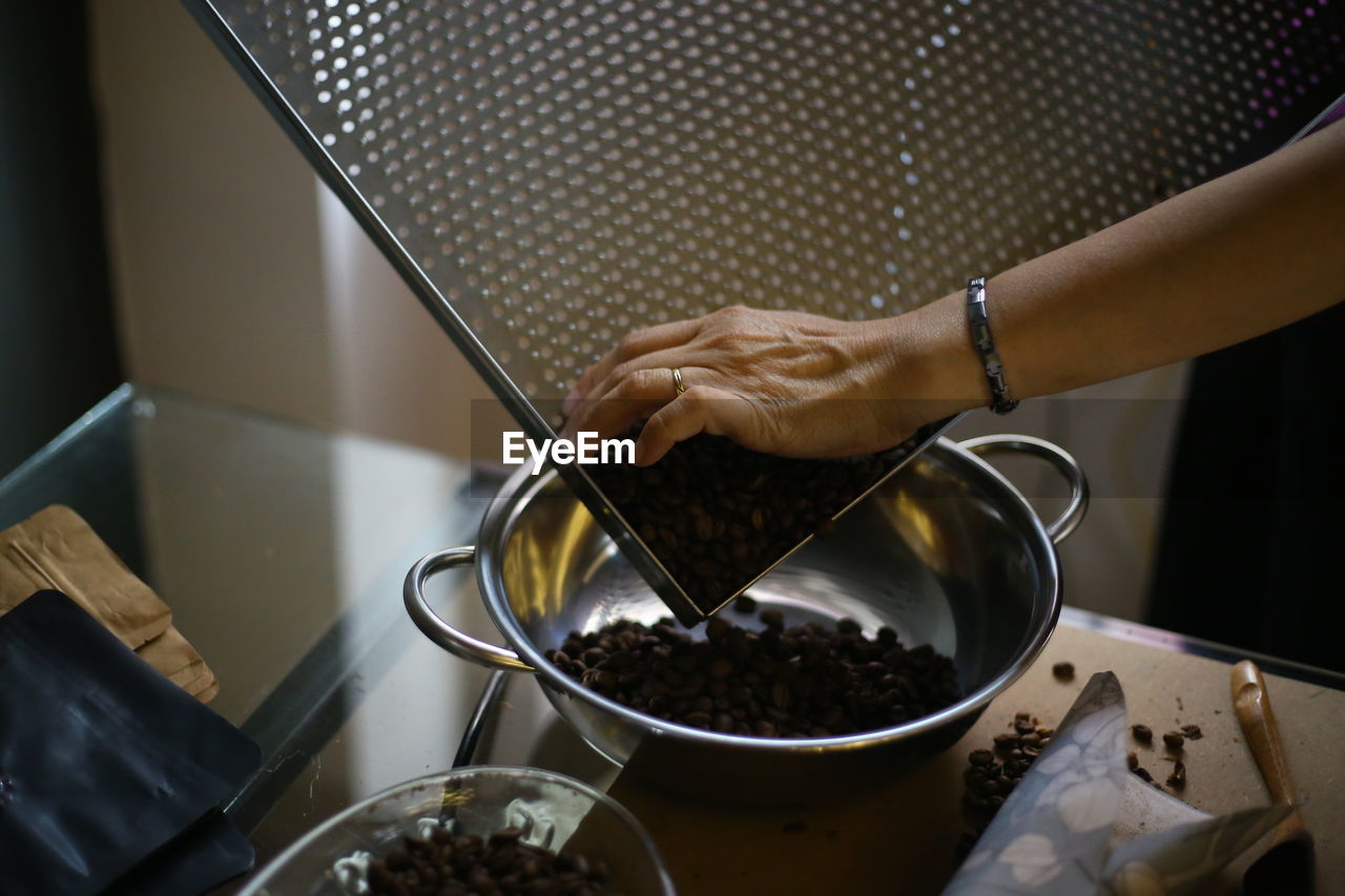 Close-up of human hand pouring chocolates in sieve