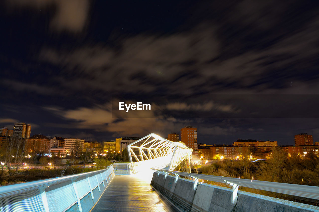 VIEW OF ILLUMINATED CITY AGAINST CLOUDY SKY