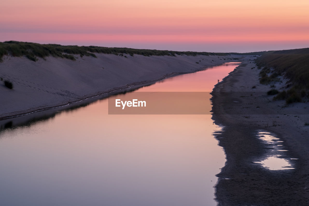 SCENIC VIEW OF LAKE AGAINST SKY AT SUNSET