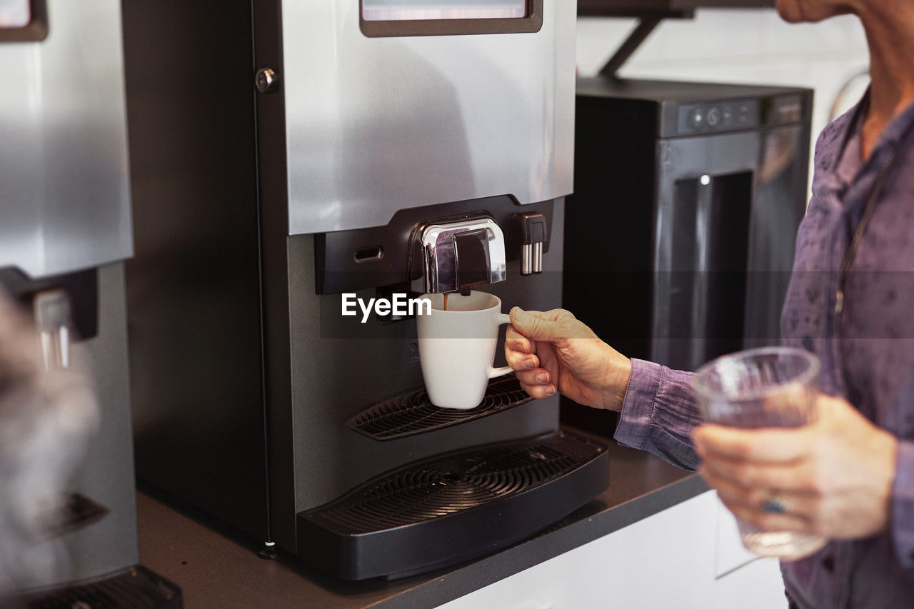 Woman preparing coffee in office kitchen