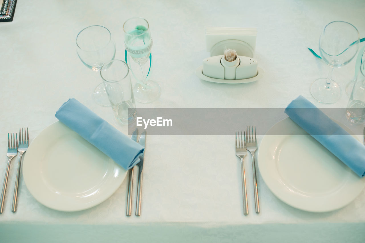 High angle view of plates and glasses arranged on table at restaurant