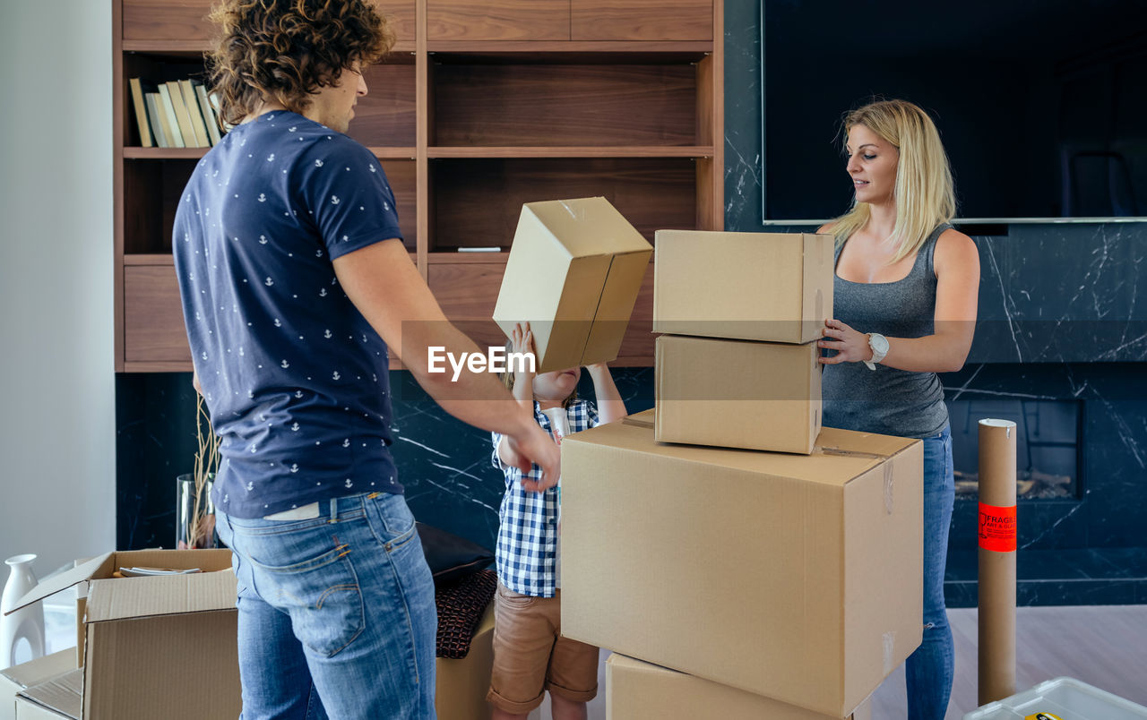 Parents with son unpacking boxes at home