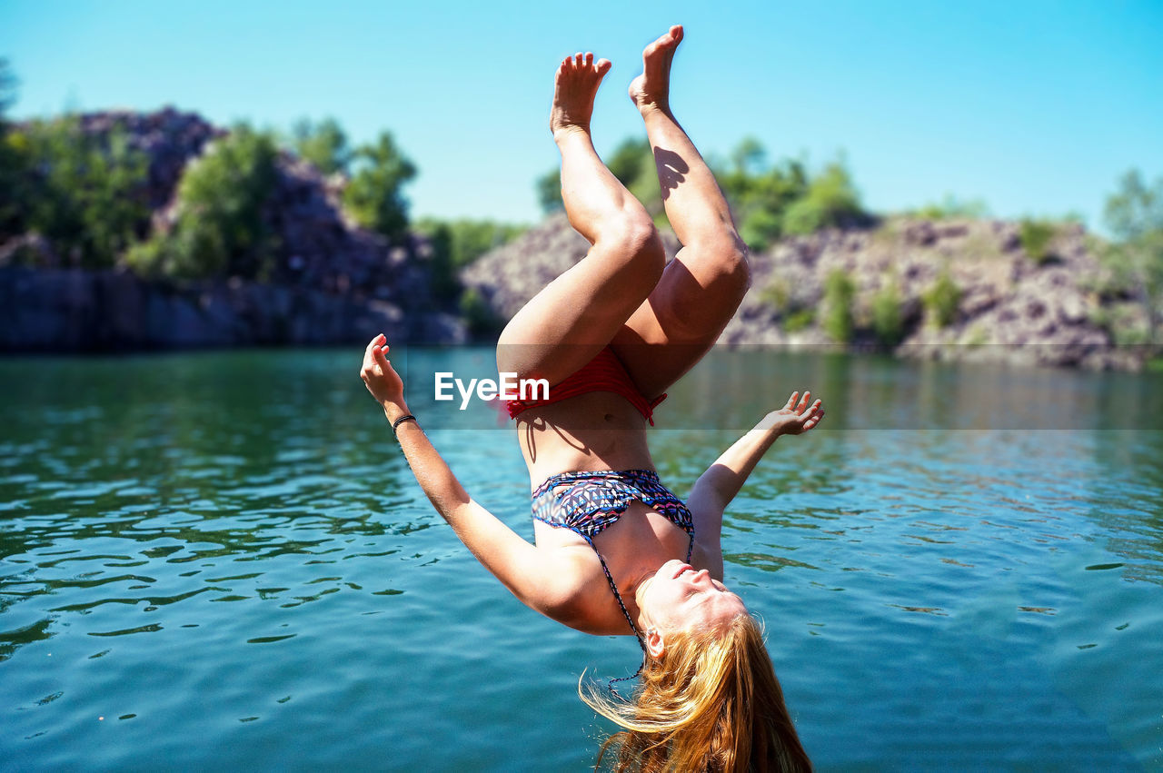 Upside down young woman diving into lake