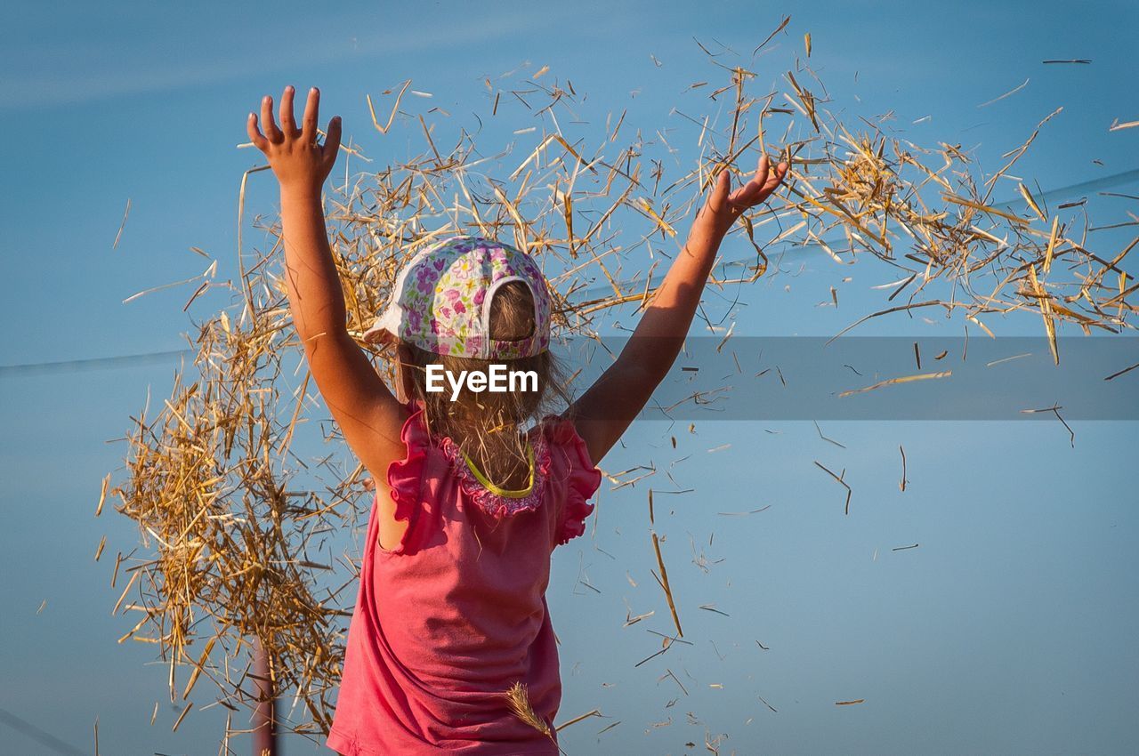 Rear view of a girl throwing up hay