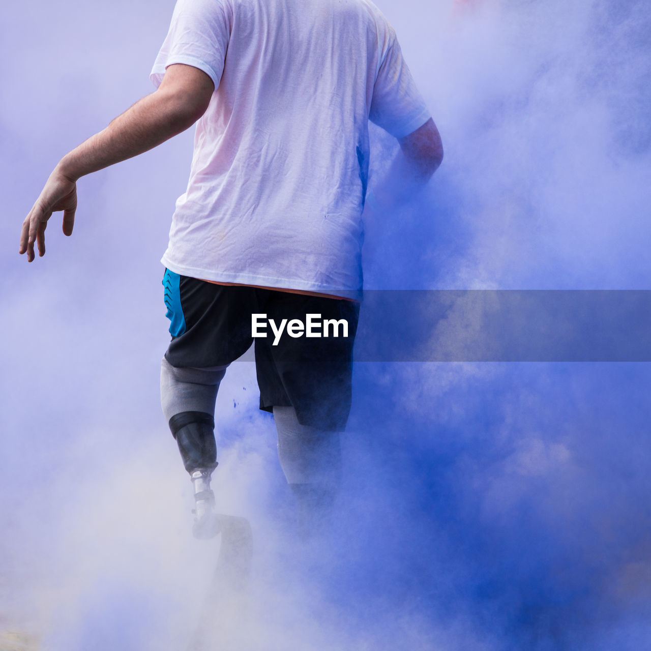 Low section of disabled person walking in blue powder paint