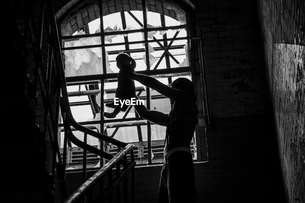 Low angle view of man holding baby boy at steps in building