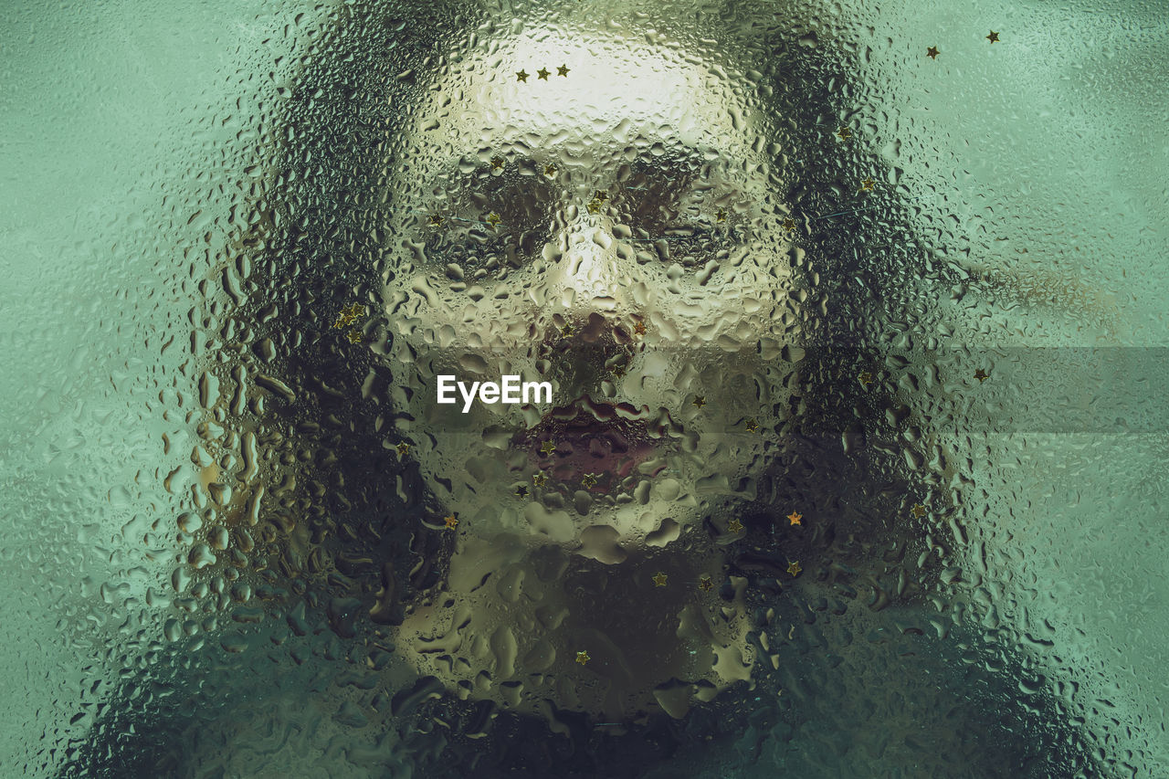 Close-up of woman seen through wet glass