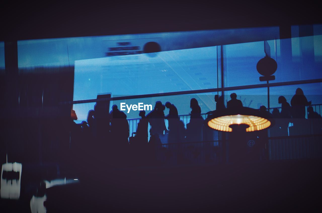SILHOUETTE OF PEOPLE IN ILLUMINATED UNDERGROUND