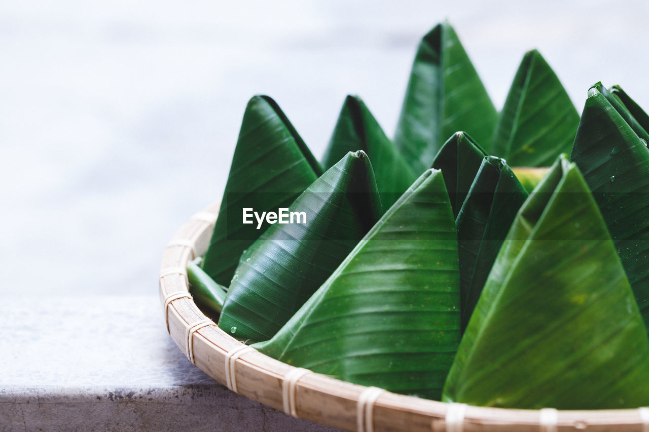 Close-up of sweet food wrapped in banana leaves in containers at table