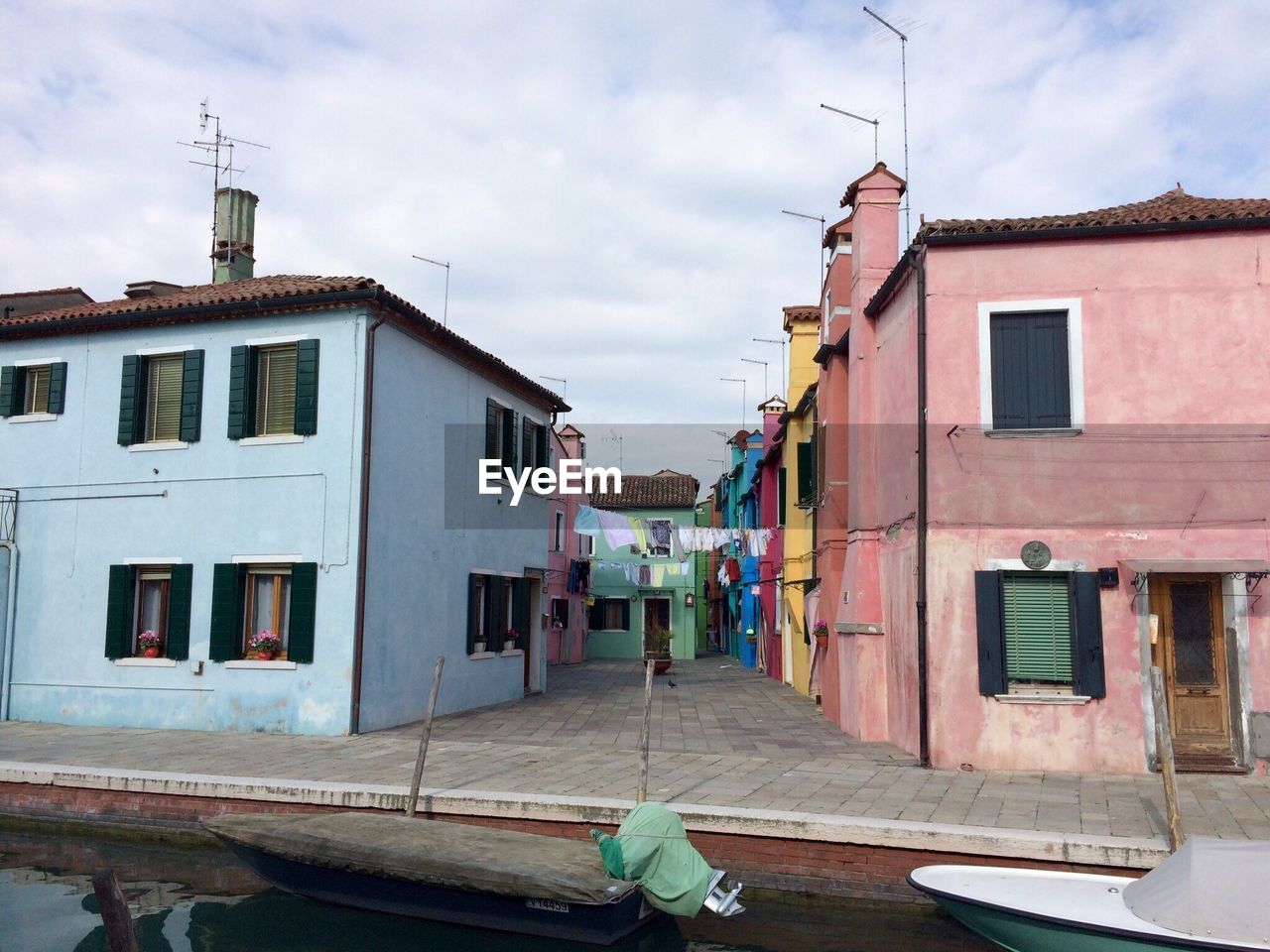 Boats in canal by houses against sky