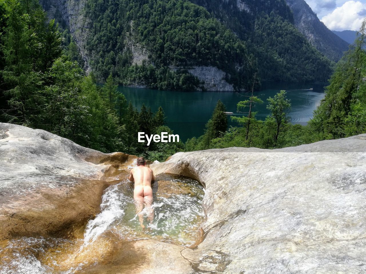 High angle view of naked man in stream against mountain