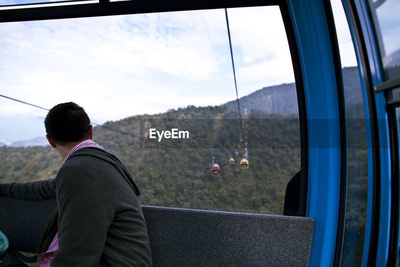 REAR VIEW OF MAN CLIMBING ON MOUNTAIN