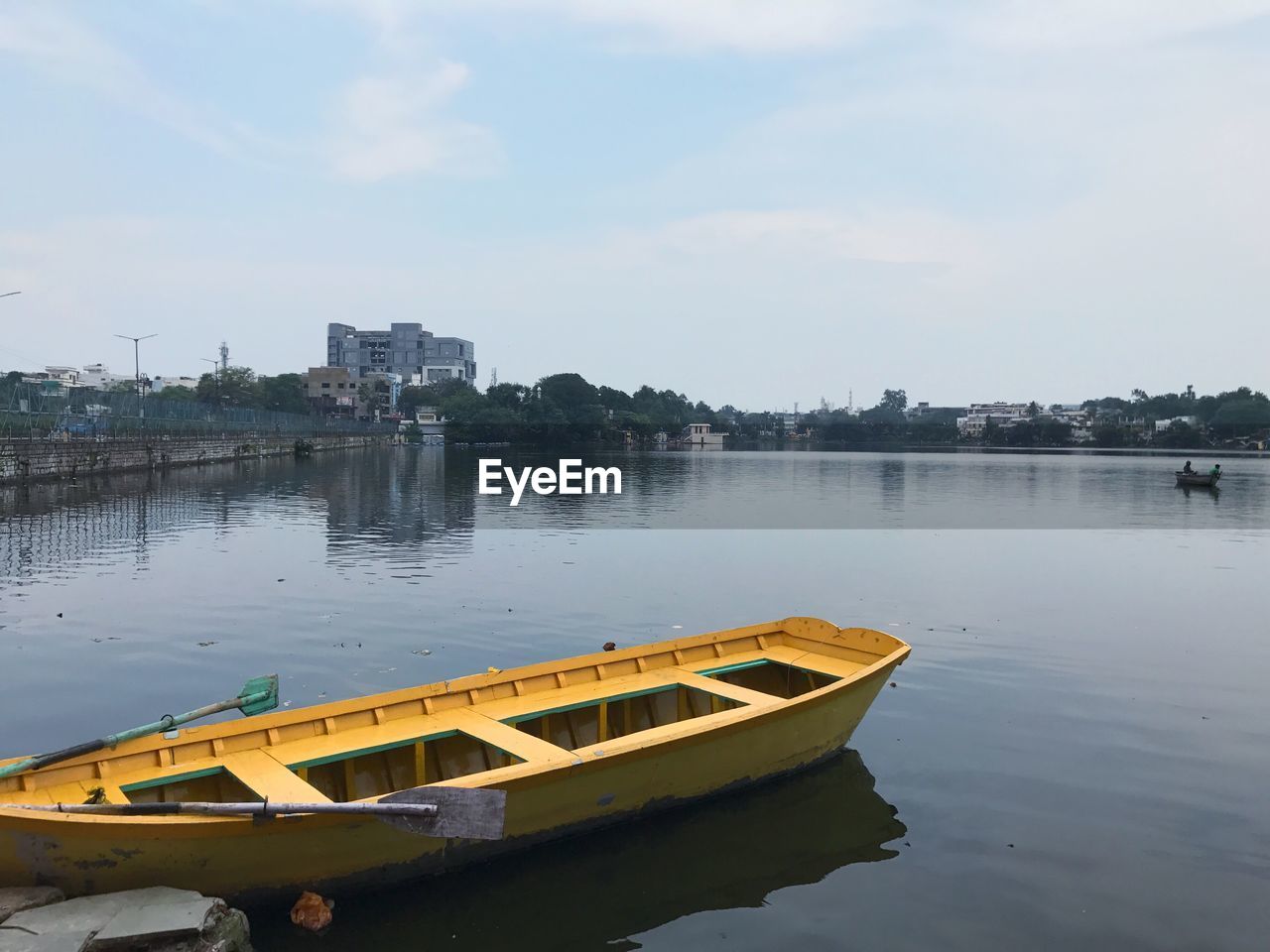 Boat moored by river against sky in city