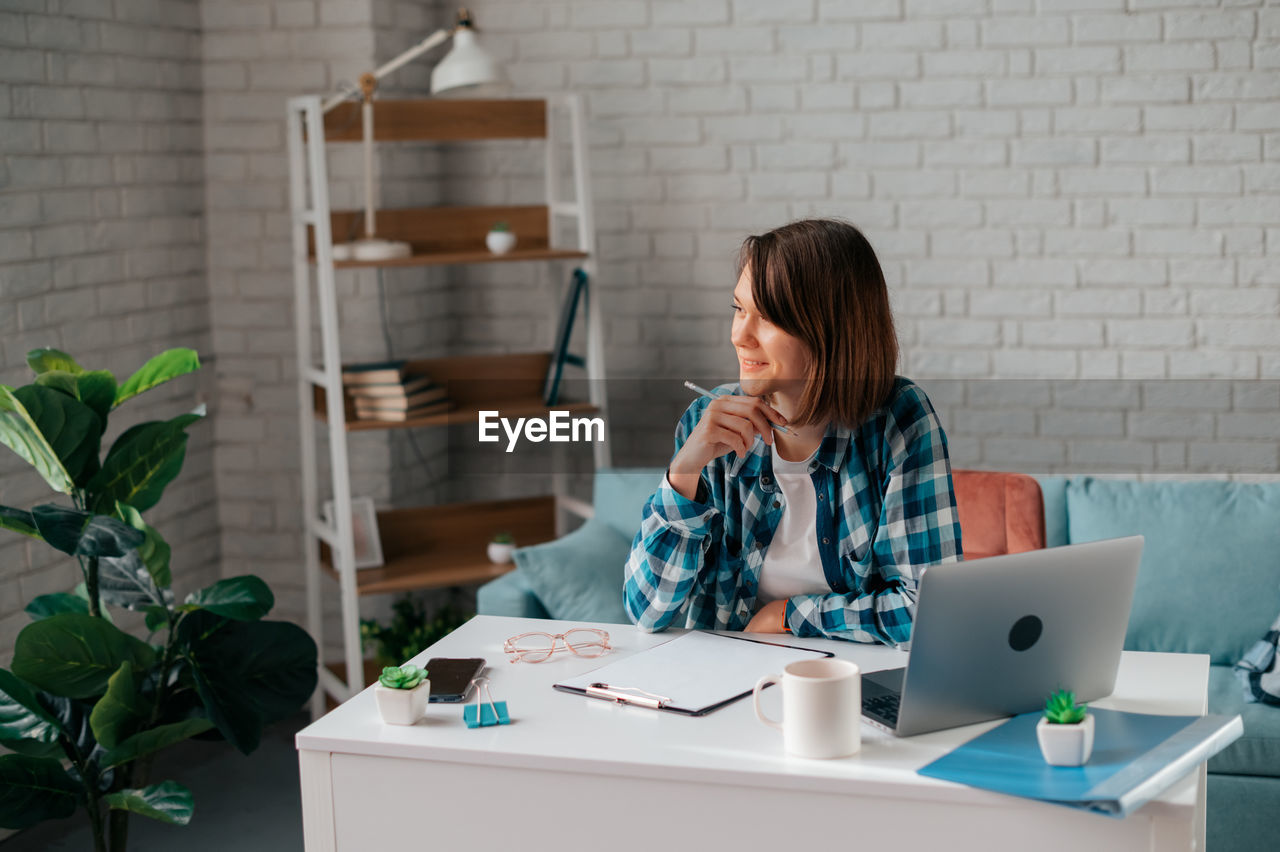 Woman looking away while working at home