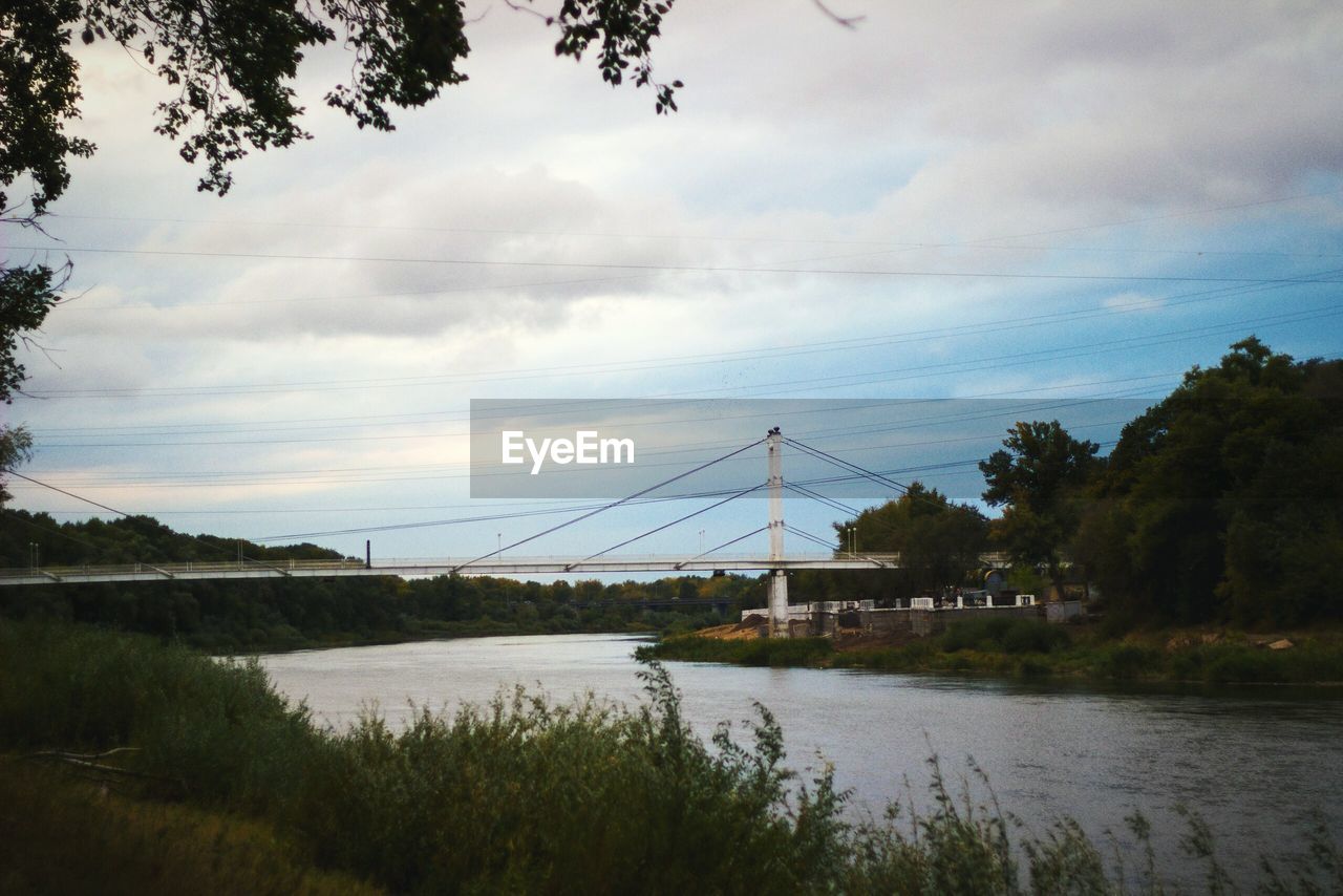 BRIDGE OVER RIVER BY TREES AGAINST SKY