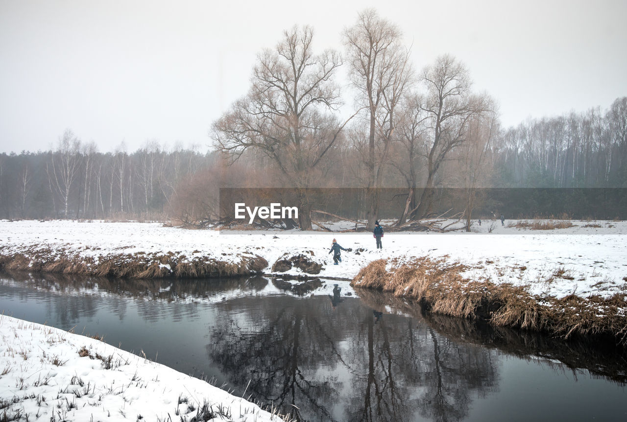 The small river flows lazily through a snowy misty winter landscape