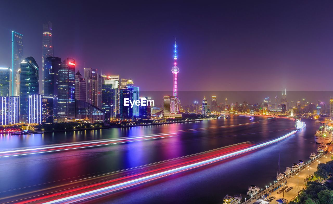 Light trails on huangpu river by cityscape at night