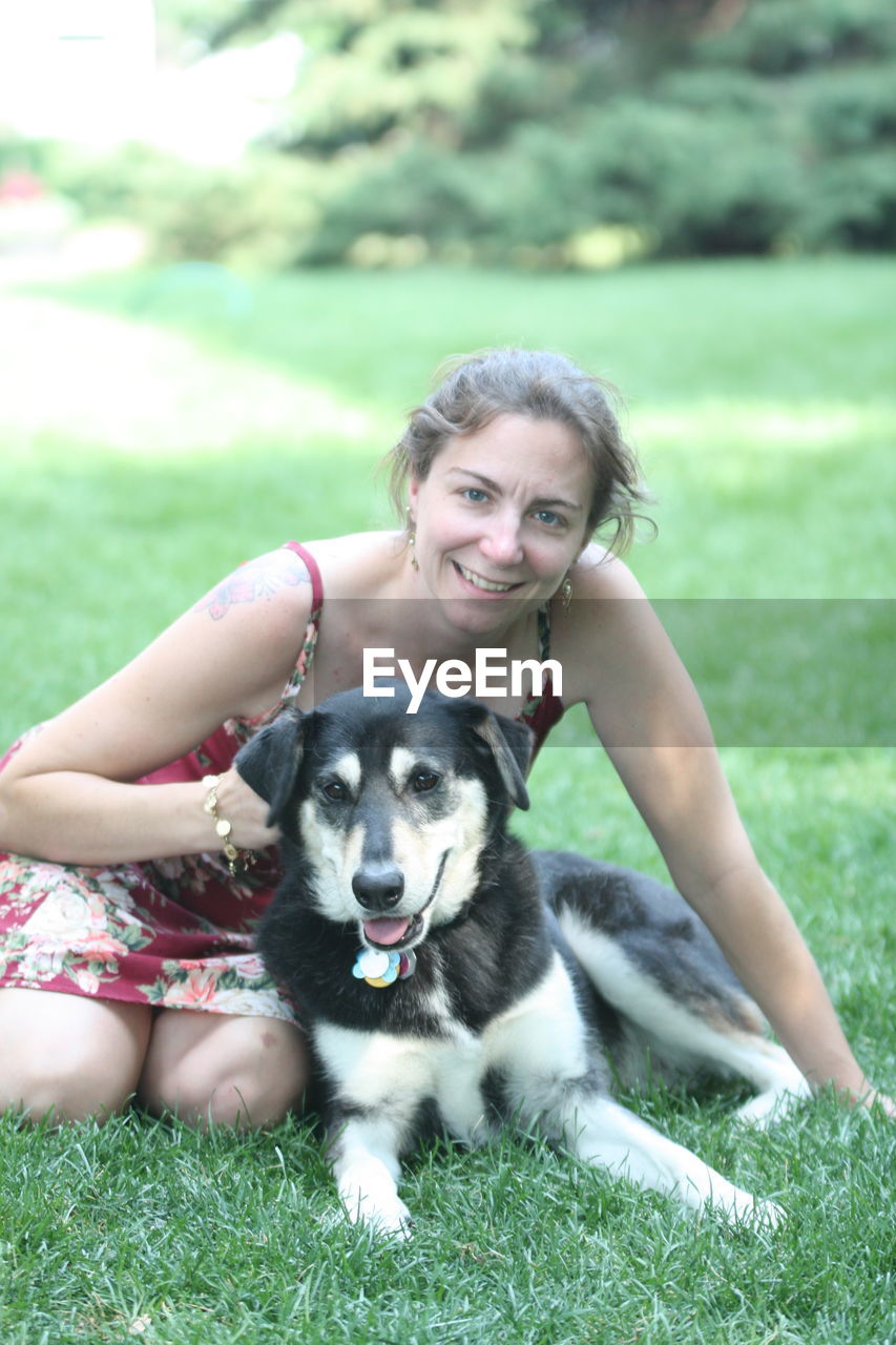 YOUNG WOMAN WITH DOG ON FIELD