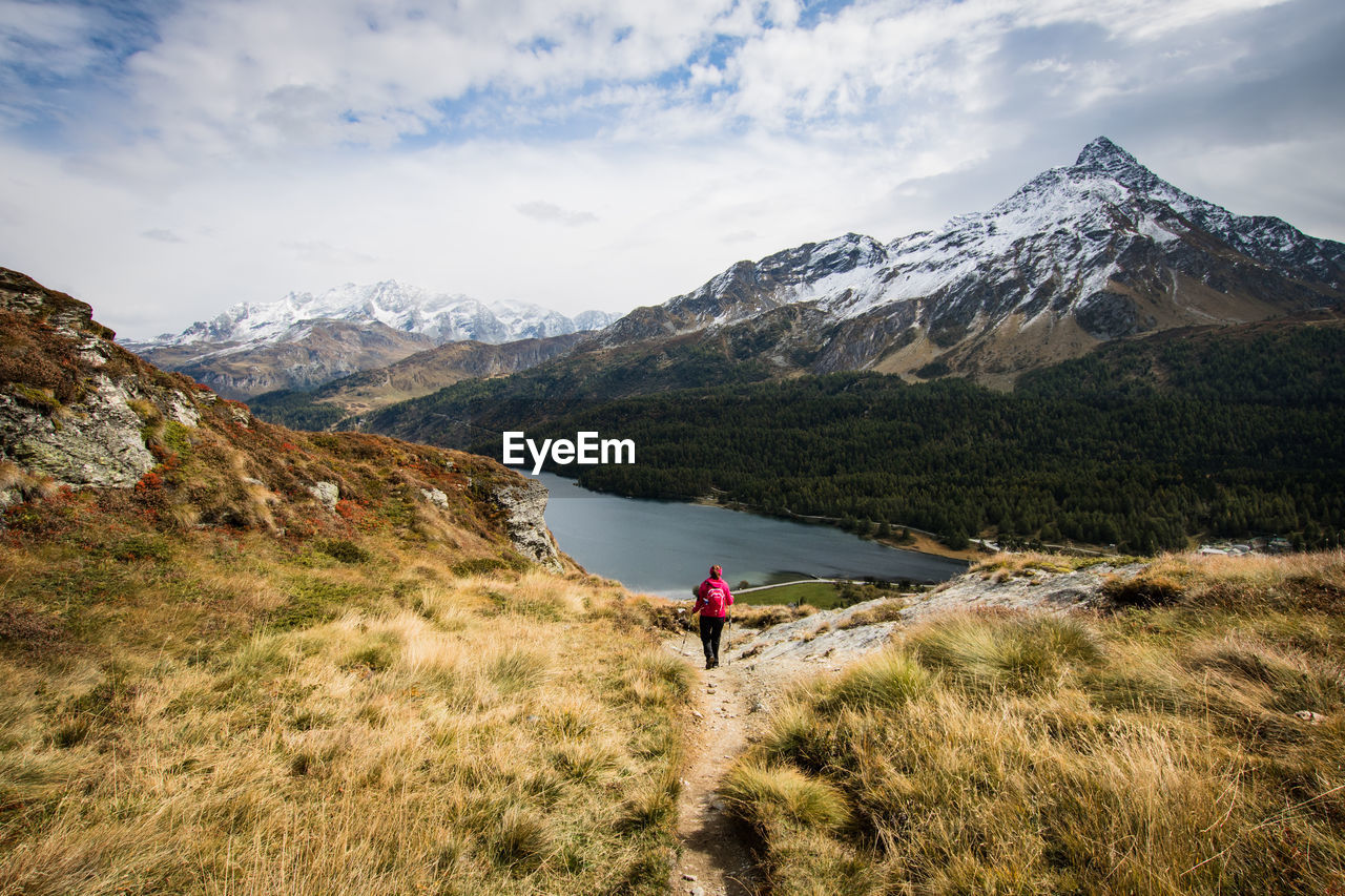 Rear view of woman hiking on mountain against sky