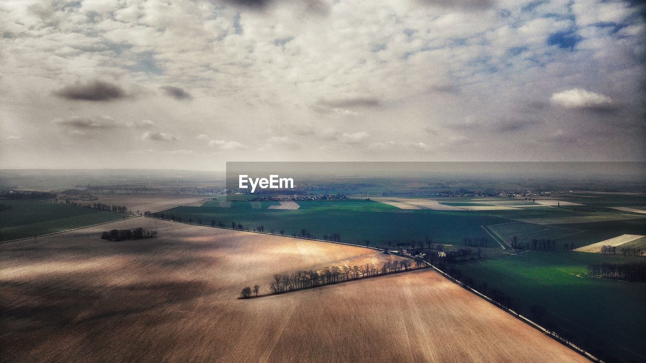 Aerial view of landscape against cloudy sky during sunset