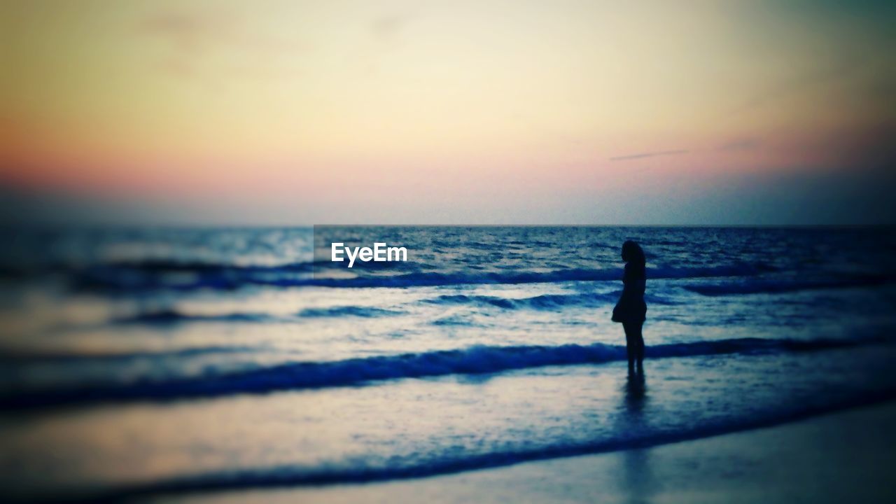 SILHOUETTE OF PEOPLE STANDING ON BEACH