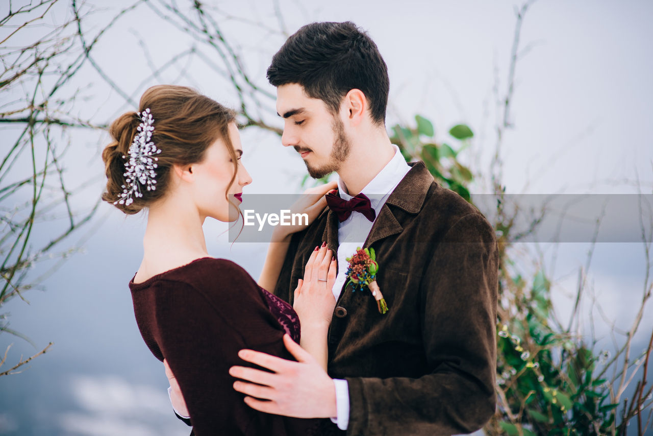 YOUNG COUPLE KISSING WHILE HOLDING PLANT