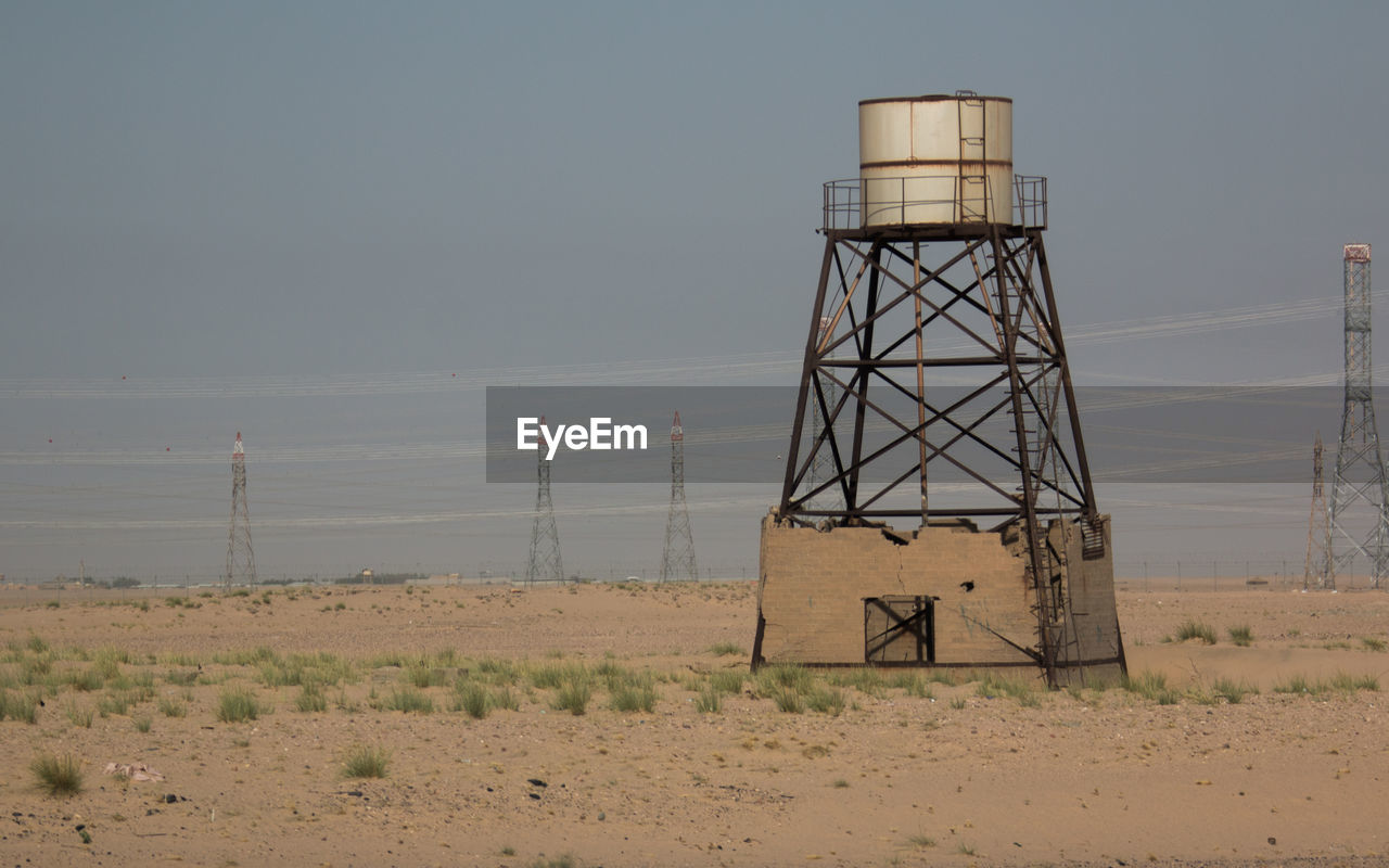 Water tower on landscape against sky