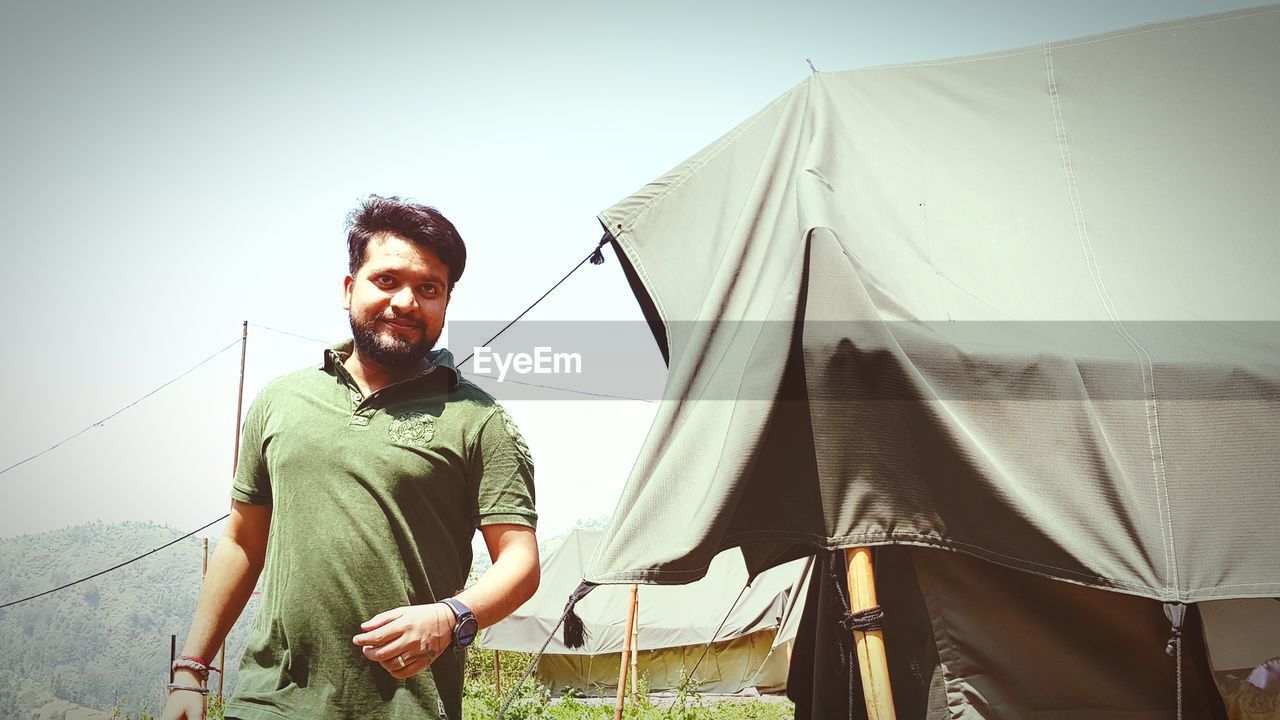 Man looking away while standing by tent