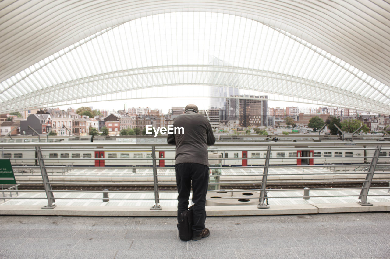 Rear view of man standing at railroad station