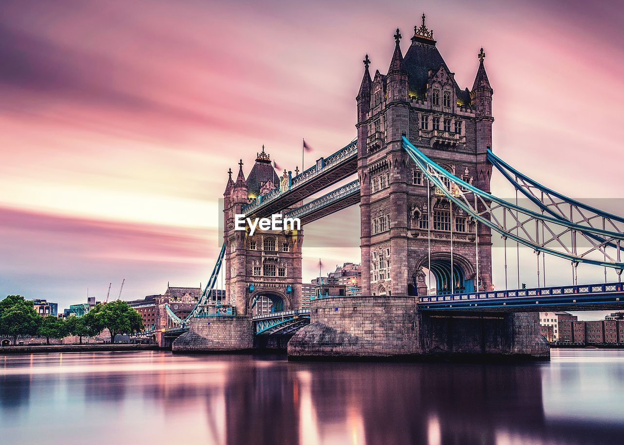 Tower bridge over river against cloudy sky