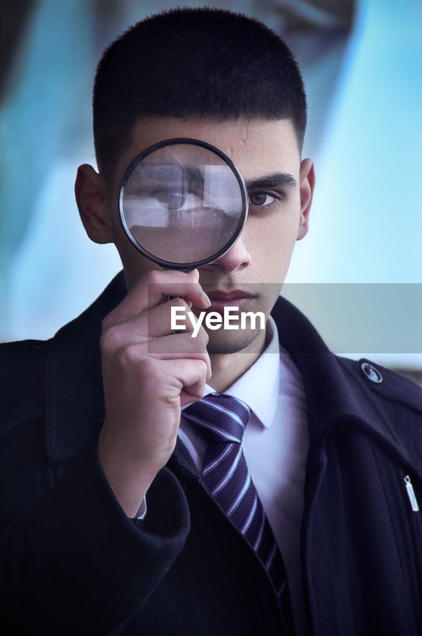 Portrait of young man holding magnifying glass