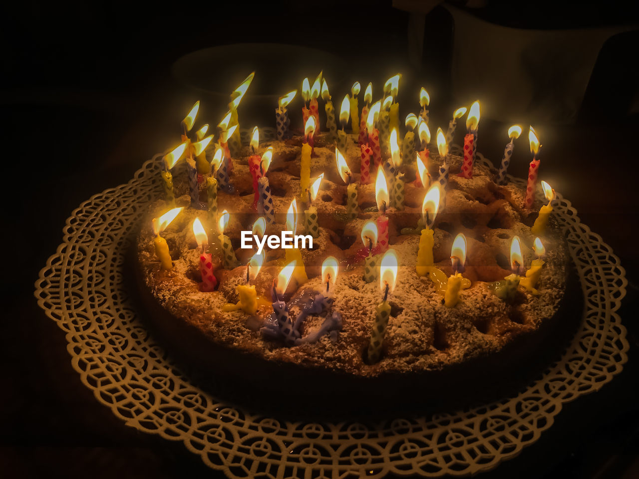 HIGH ANGLE VIEW OF CAKE WITH ILLUMINATED CANDLES ON TABLE