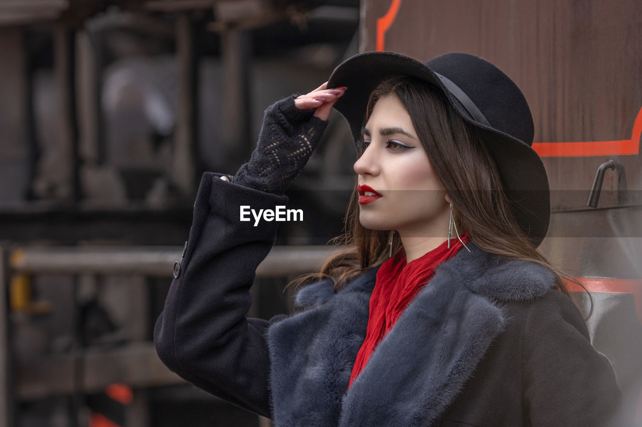 portrait of young woman wearing hat standing outdoors