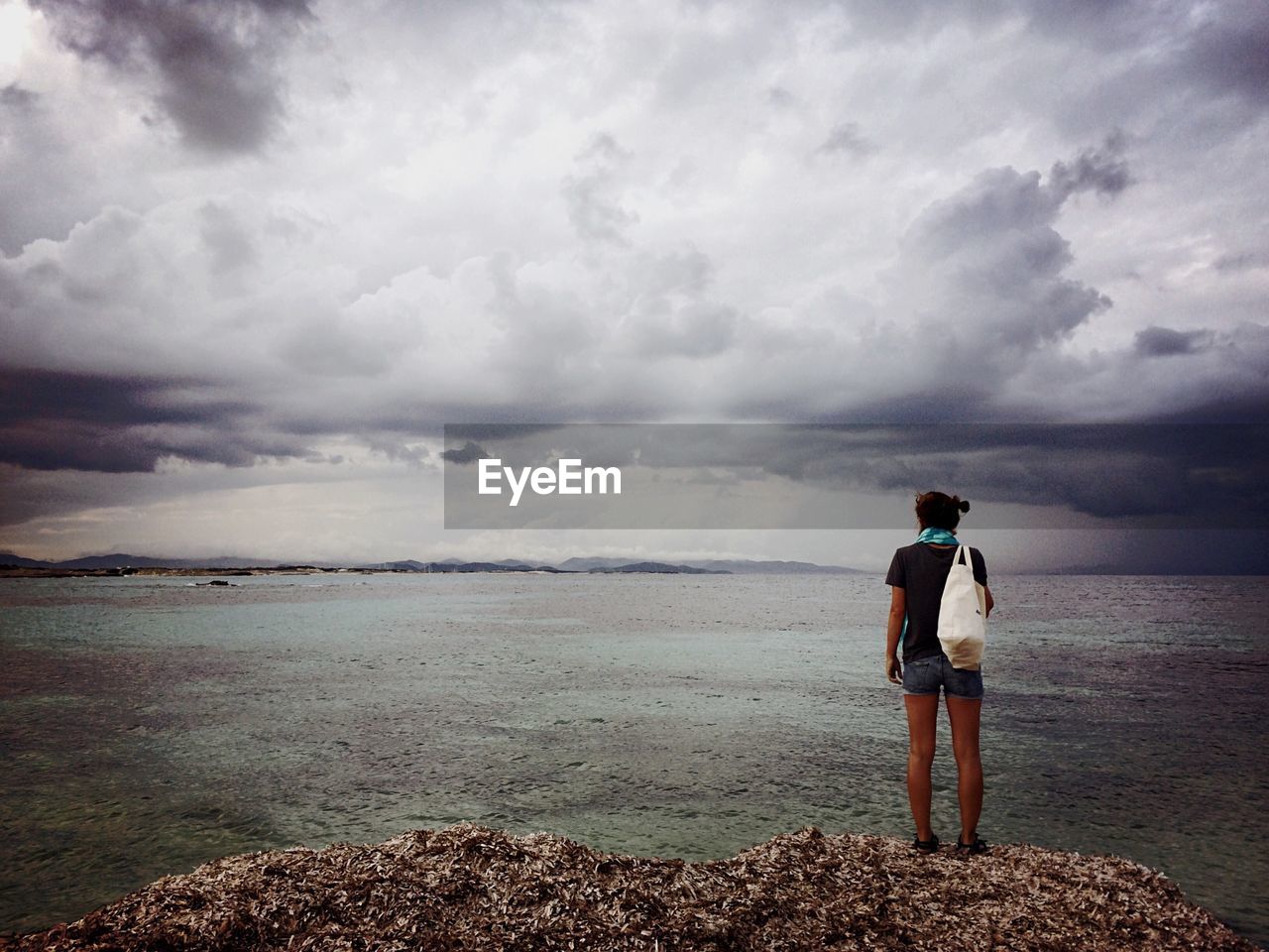 Rear view of woman standing on beach against sky