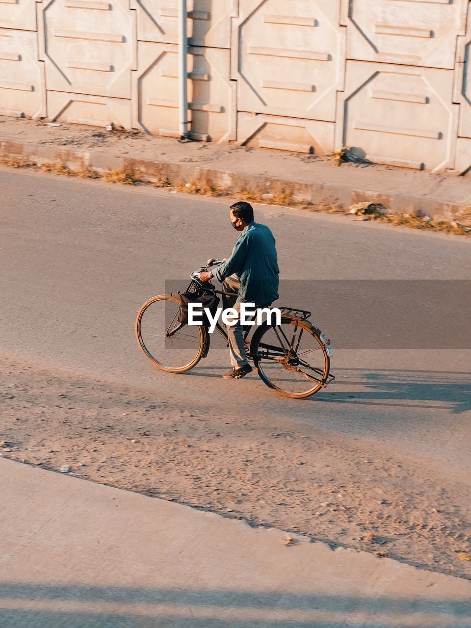 Rear view of man riding bicycle on road