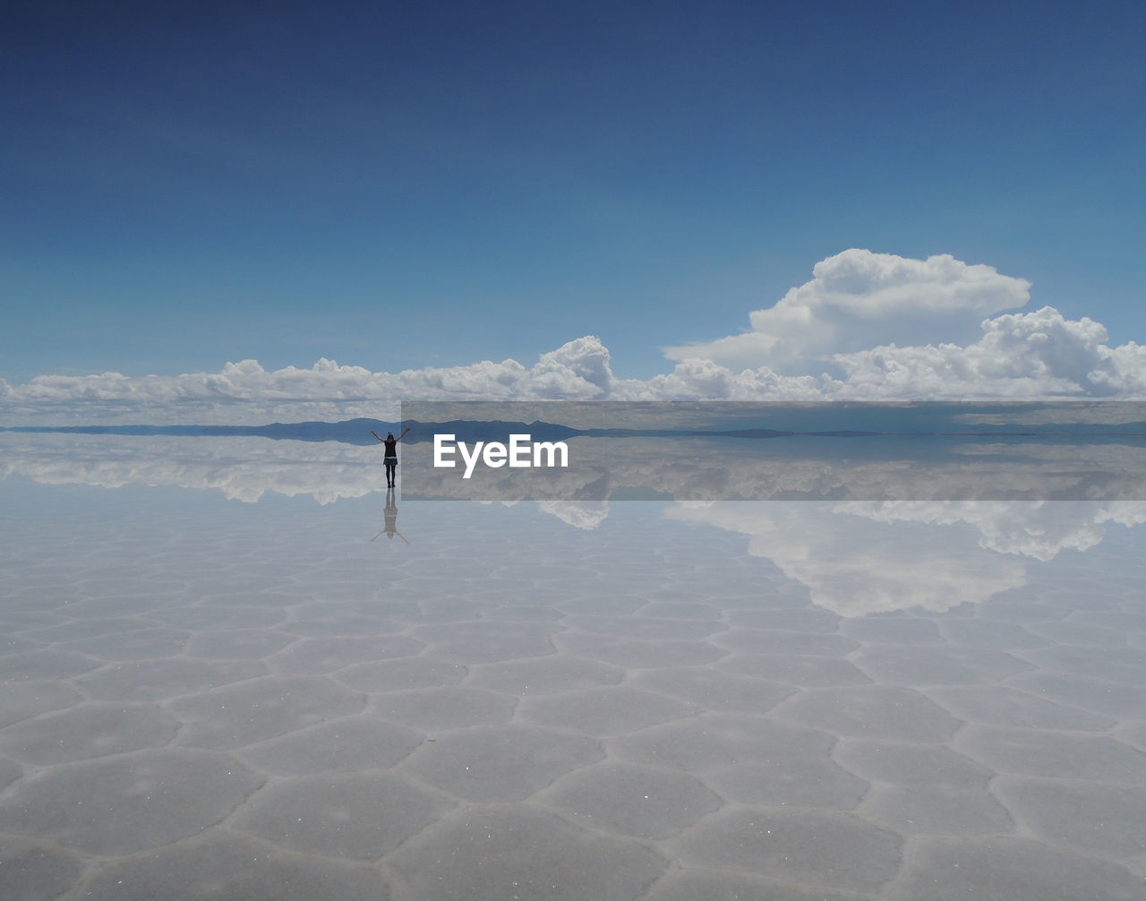 Mid distance view of woman standing on shore against sky