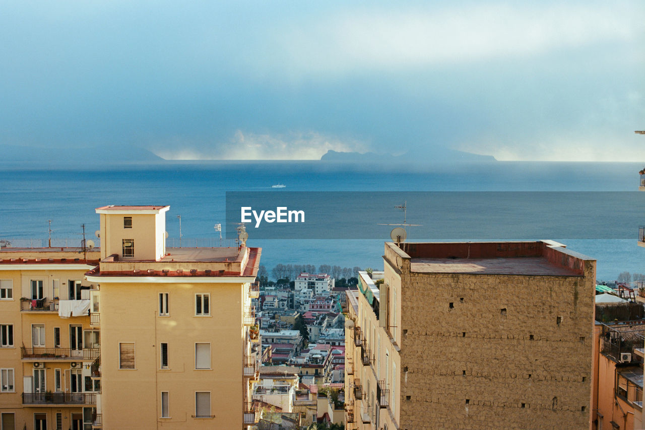 HIGH ANGLE VIEW OF BUILDINGS AGAINST SEA